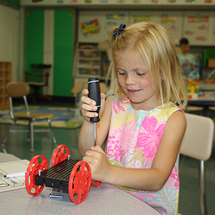  Young girl using a screw driver to assemble a STEM project.